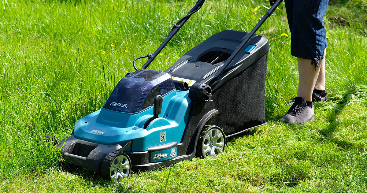 person using a cordless battery powered lawn mower
