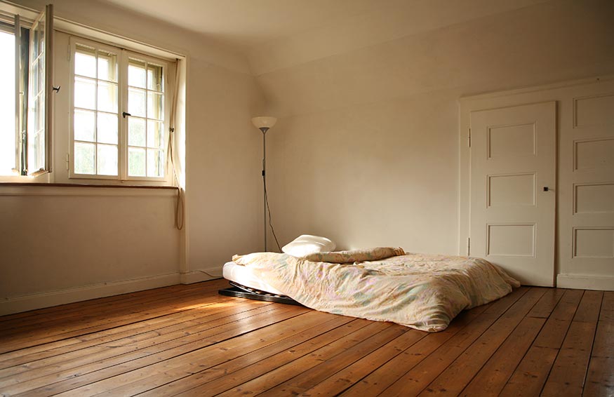 A mattress on a wooden floor in a room.