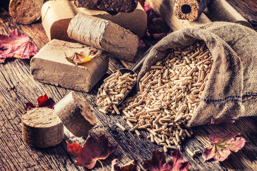 Wooden pressed pellets and briquettes from biomass with autumn leaves.