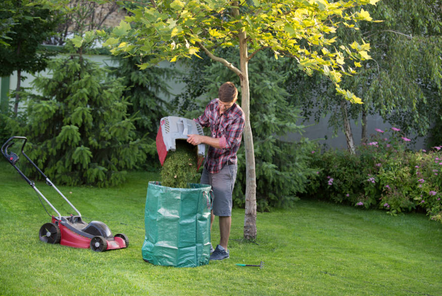 man emptying lawn clippings into compost bag