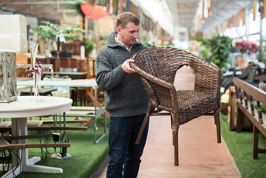 man inspecting wicker chair in furniture store