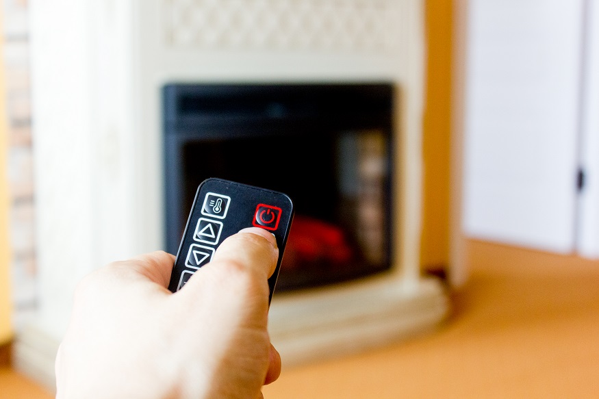 a person using the remote to lower the temperature of the electric fireplace
