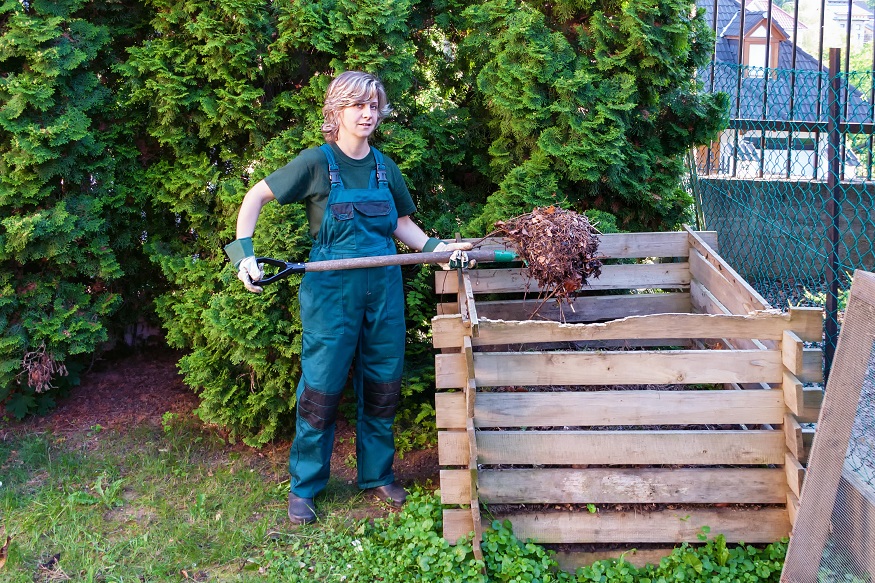 woman turning compost pile