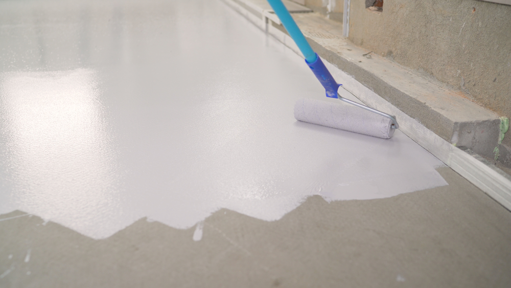 man using a paint roller to apply garage floor paint