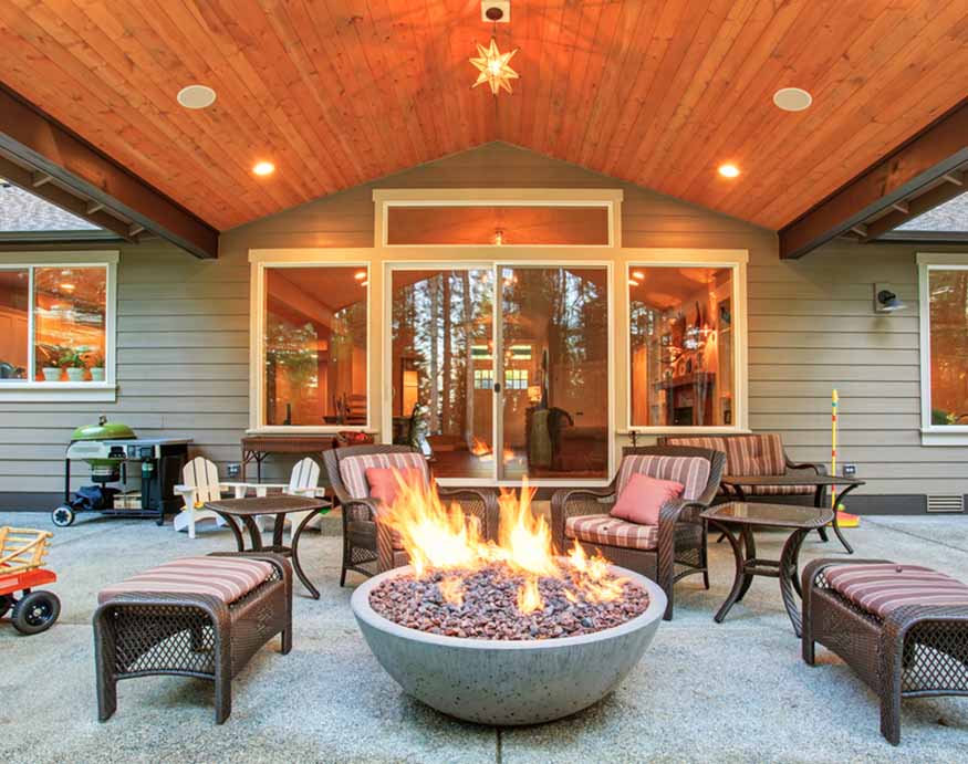 large backyard with burning lava rocks in the fire pit