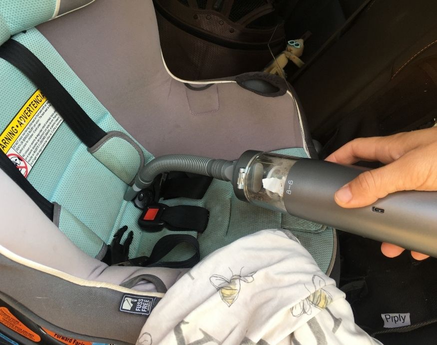 A person using the Brigii M1 to clean a baby car seat