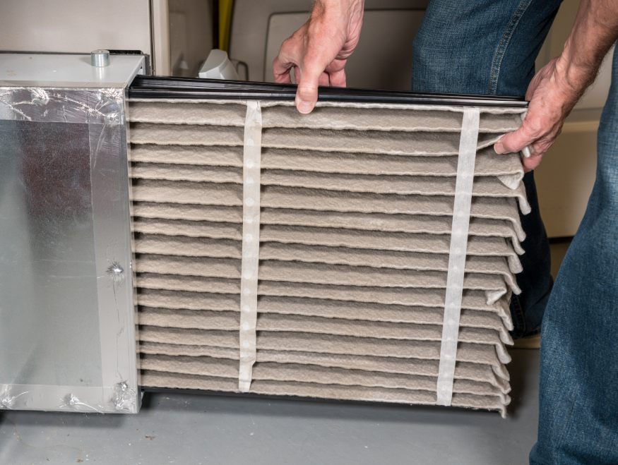 a homeowner replacing an HVAC’s dirty filter
