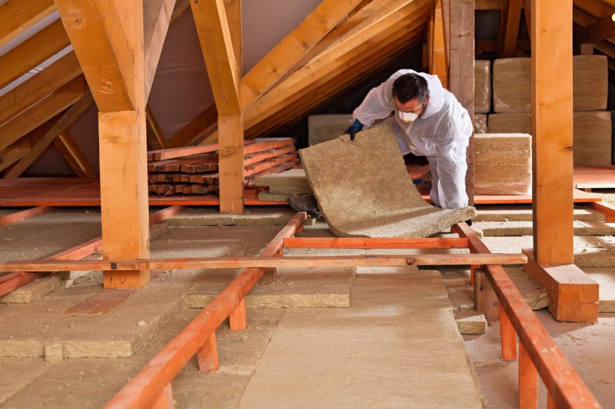 a worker adding thermal insulation in the attic