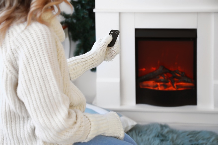 A woman sitting next to an electric fireplace