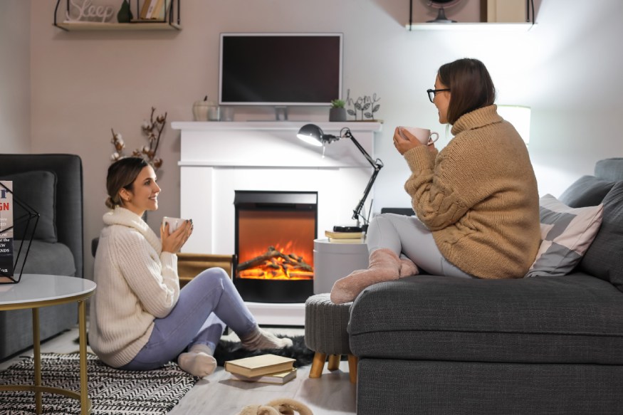 Friends sitting next to an electric fireplace