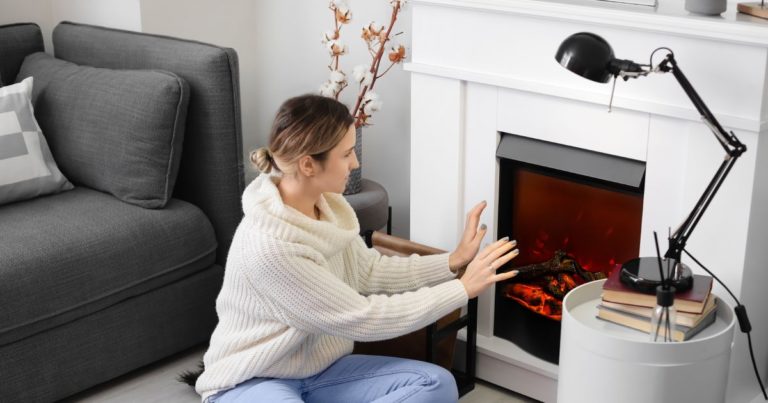 A woman is sitting in front of a fireplace.