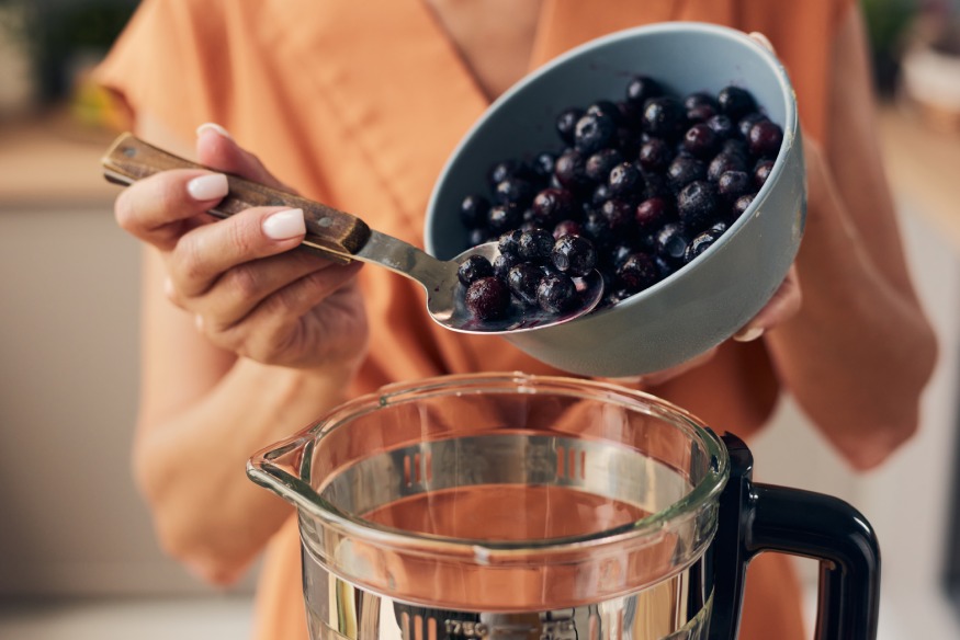 woman putting blueberries in the blender
