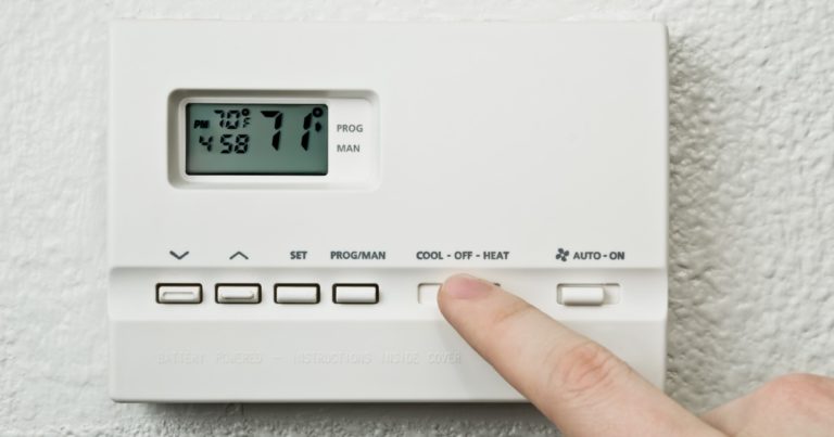 a person pushing the emergency heat button on the thermostat