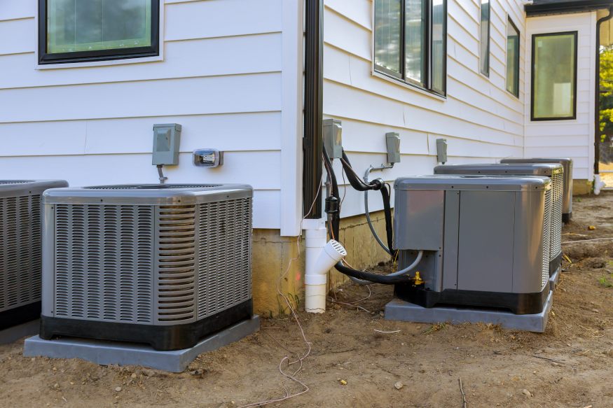 Several AC units resting on a level air conditioner pad or base