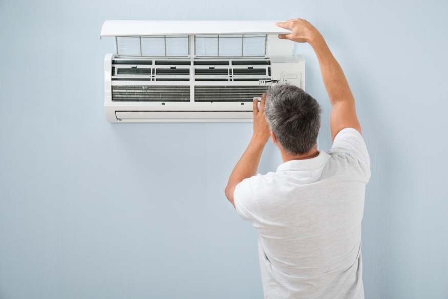 A person checking an air conditioning unit