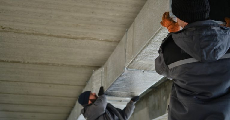 two men installing a metal duct