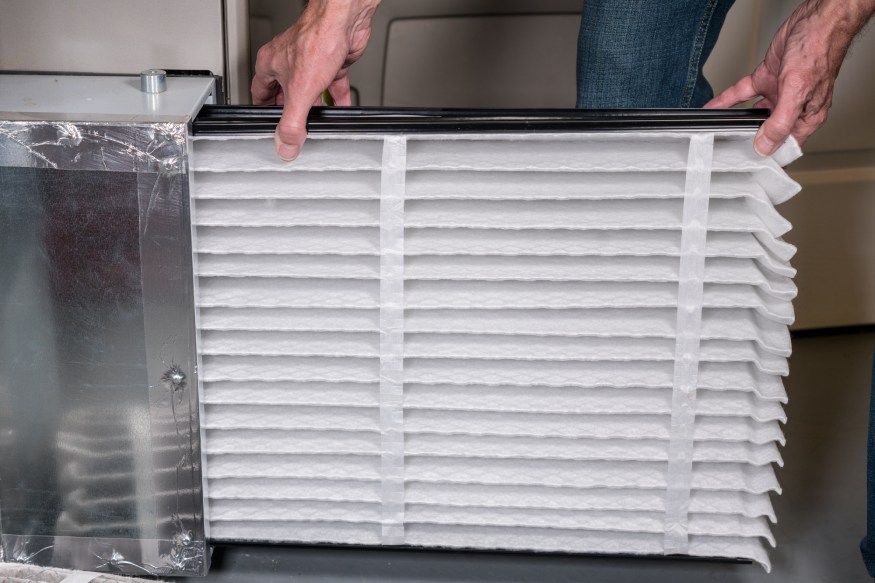 A person installing a brand-new and clean HEPA filter