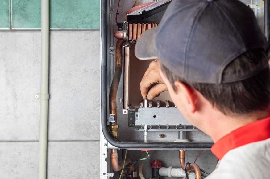 A man is working on a hot water heater.