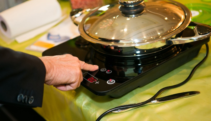 a person adjusting the temperature of a portable induction unit
