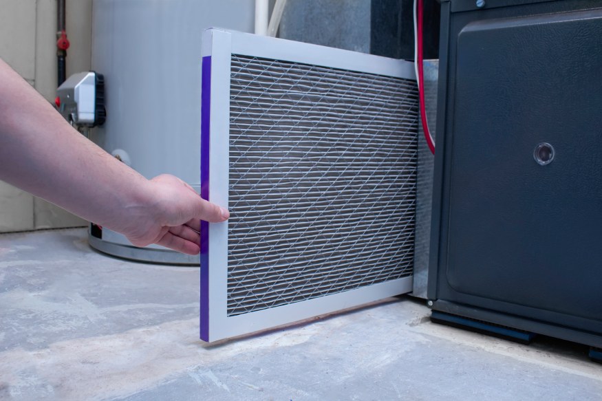 a person removing a dirty furnace filter