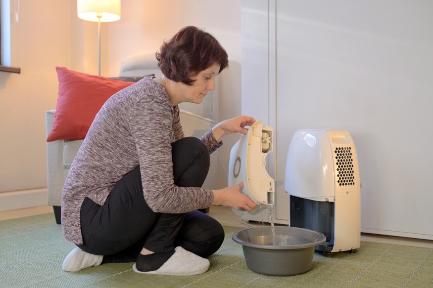 a woman emptying the tank of a dehumidifier