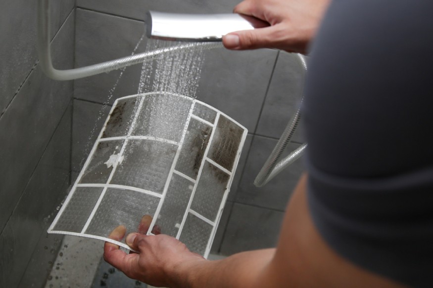 a person washing a portable air conditioner’s filter