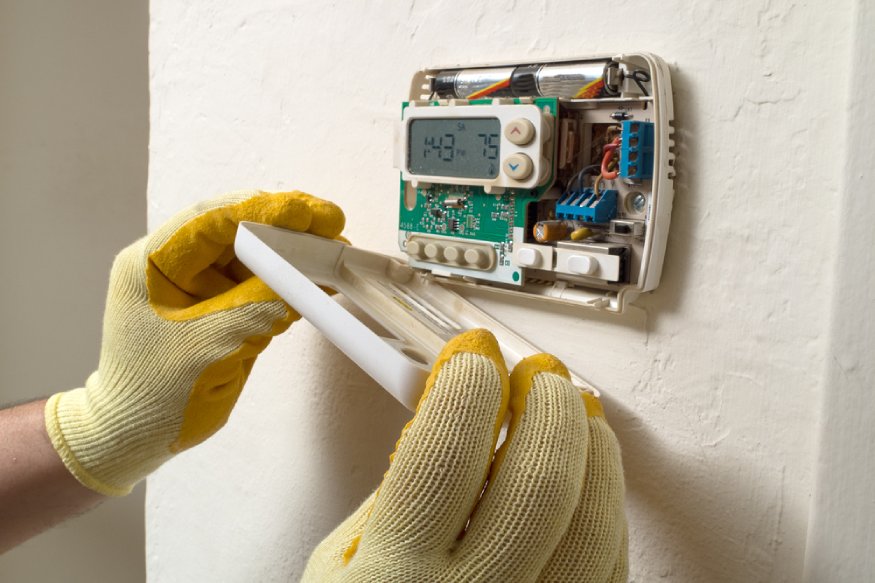 a technician installing a thermostat