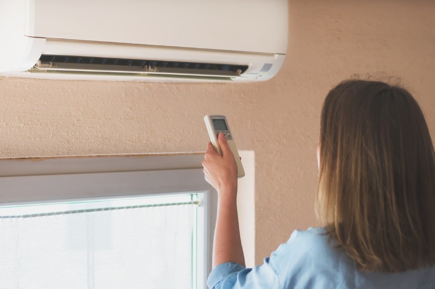 a woman using the remote to set the temperature of a mini-split ac