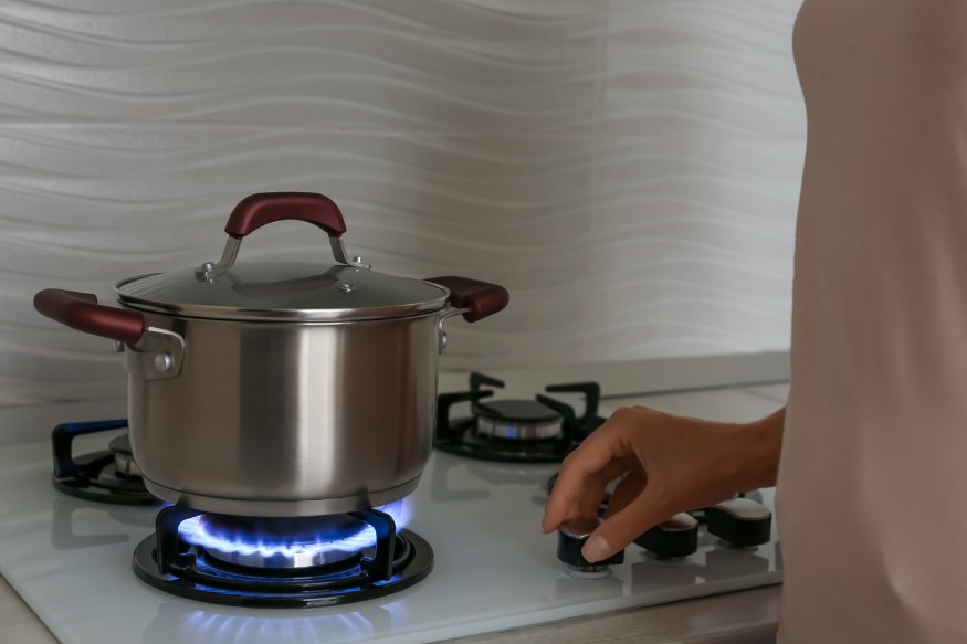 woman turning the gas stove on to boil water