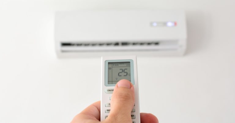 a person using the AC’s remote to adjust the temperature