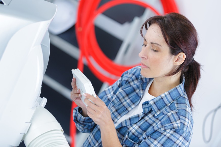 a woman checking the thermostat of a portable air conditioner