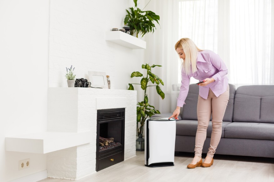 a woman turning on a dehumidifier in the living room