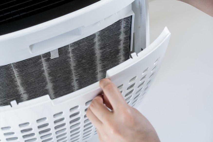 a person inspecting the portable AC’s filter