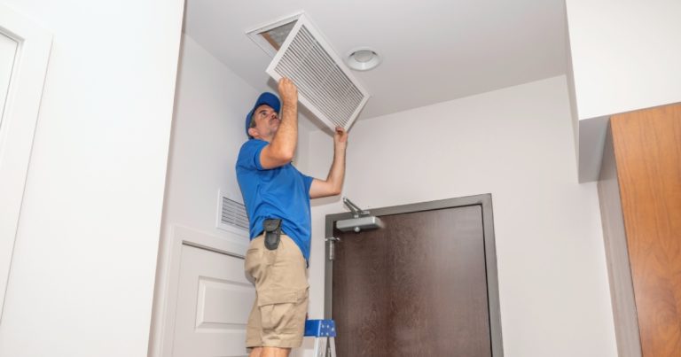 an HVAC technician checking the return air vent filter