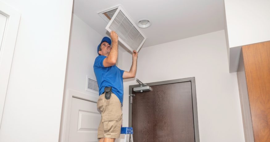 an HVAC technician checking the return air vent filter