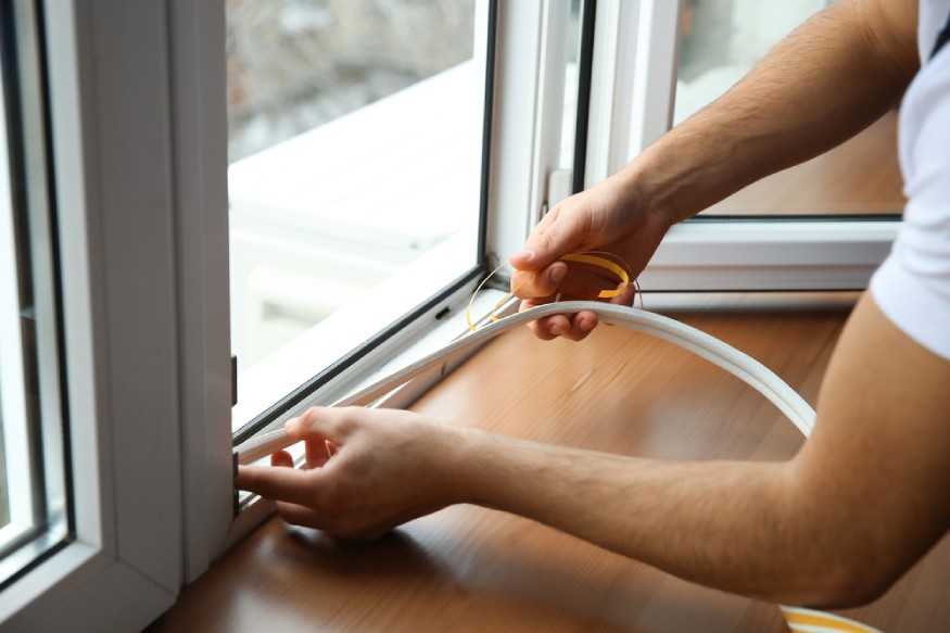 a person adding weatherstripping to the windows