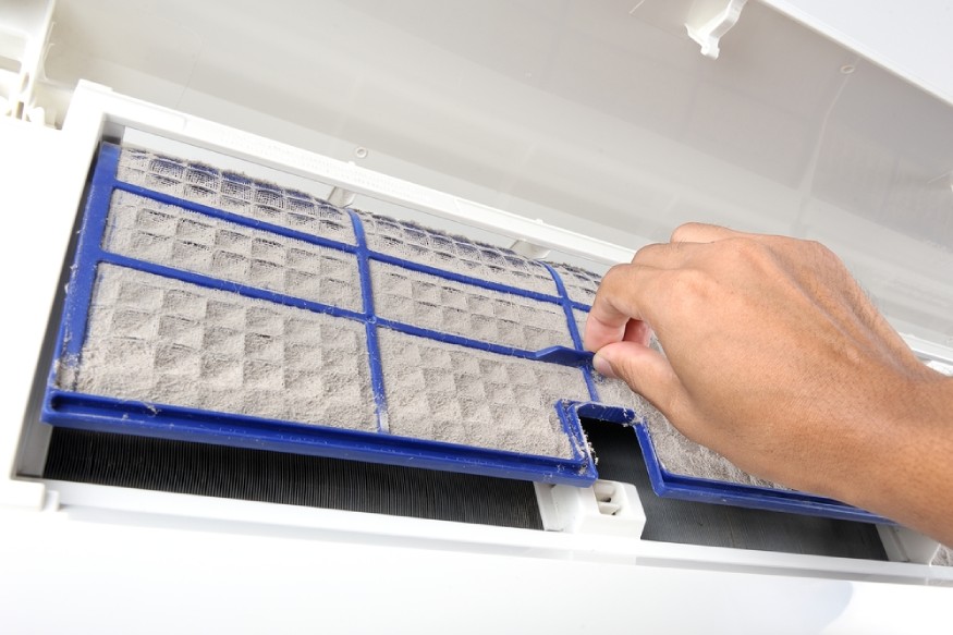 a person removing a dirty, clogged ac filter