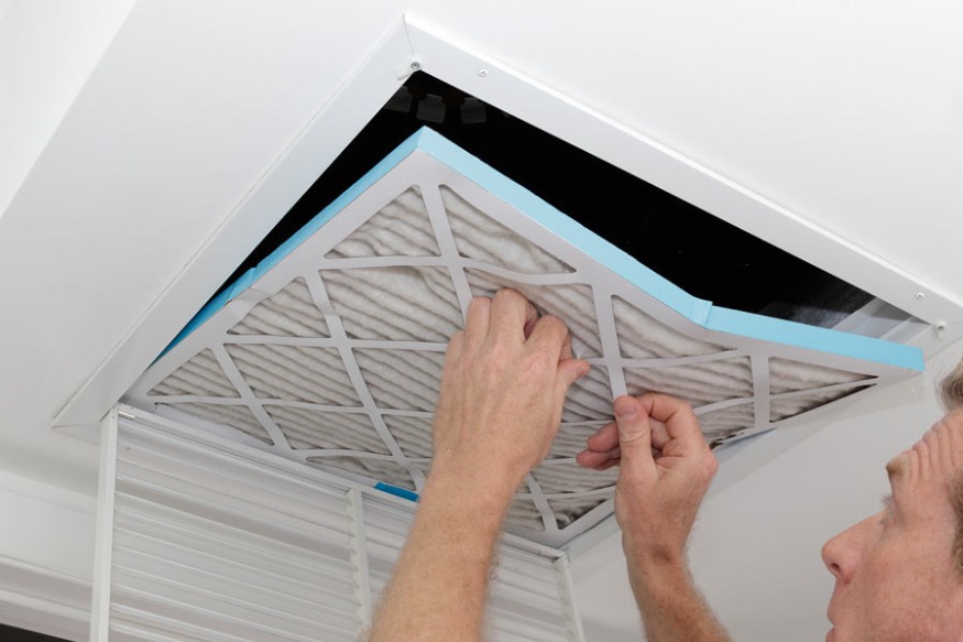 a person removing a dirty pleated air filter