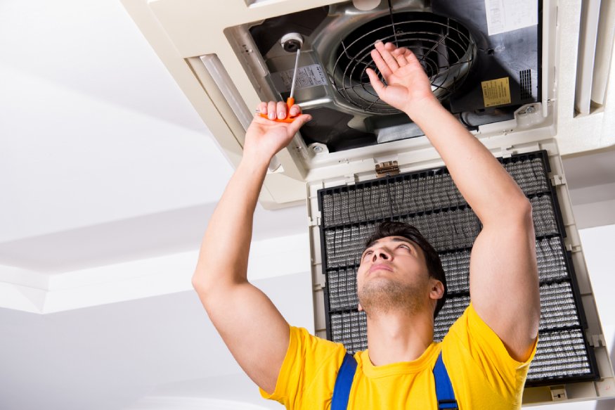 technician checking the fan of a central AC unit