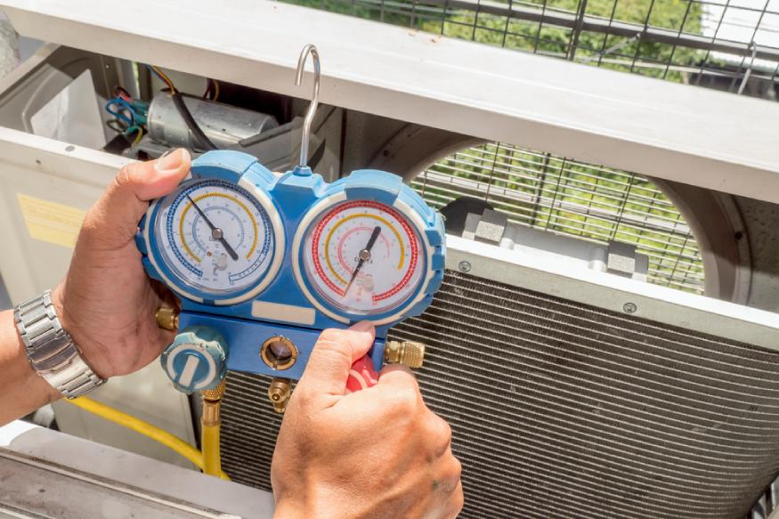a technician using a manometer to check the AC’s refrigerant levels