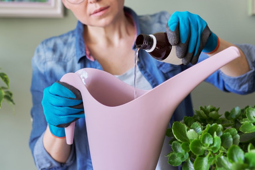 a woman pouring a bottle of liquid fertilizer into a watering can