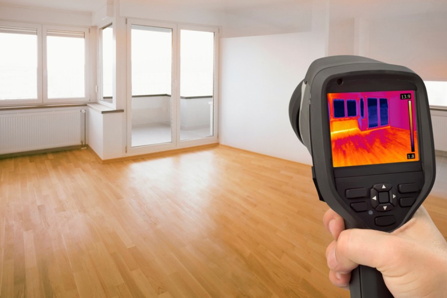 a person using an infrared thermometer gun to check the temperature of a 2-story home