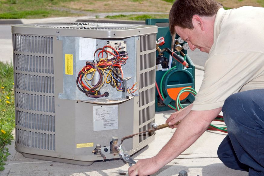 HVAC professional checking the outdoor unit of an AC