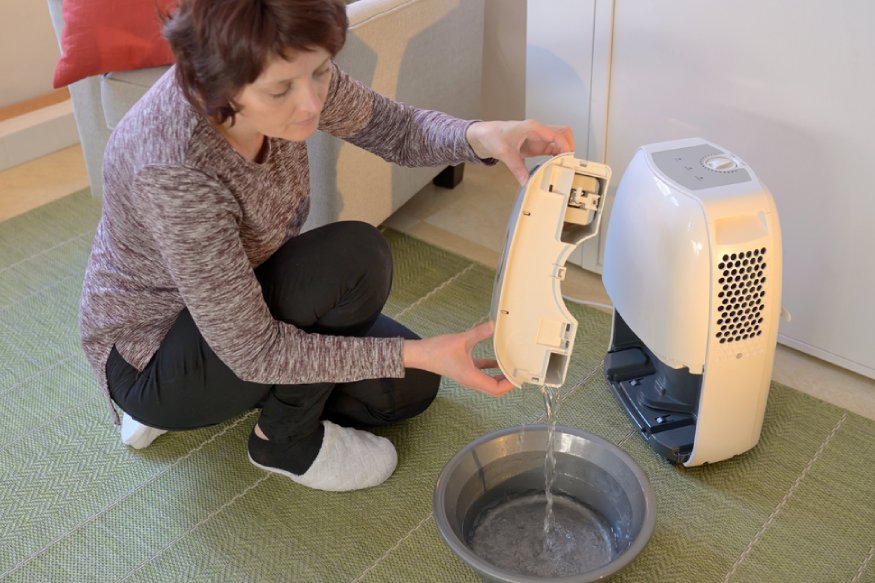 a woman emptying a dehumidifier’s reservoir