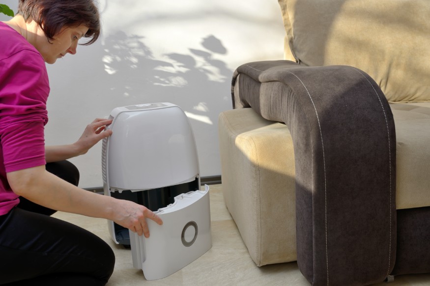 woman checking the water reservoir of a dehumidifier