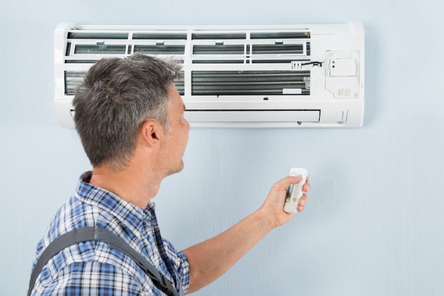 a technician using a remote control to operate a ductless mini-split AC