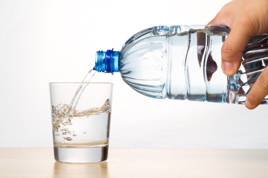 woman pouring distilled water to a cup.