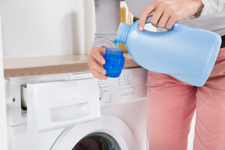 woman pouring liquid detergent to a cup