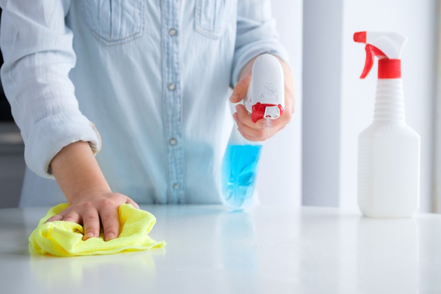 a person using a surface cleanser spray to clean the countertop