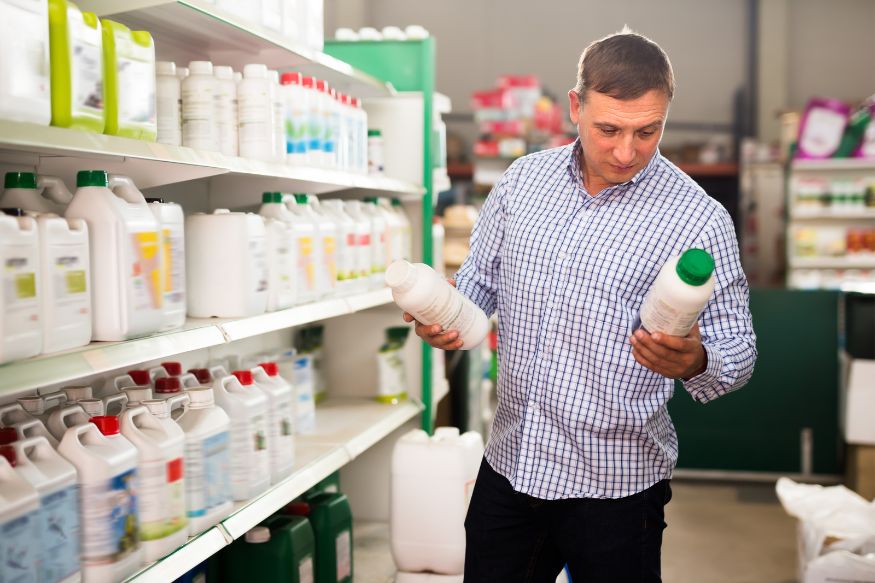 man reading the label of liquid fertilizers